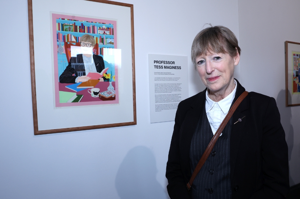Nominee Tess MaGinnis standing in front of her portrait in the Naughton Gallery